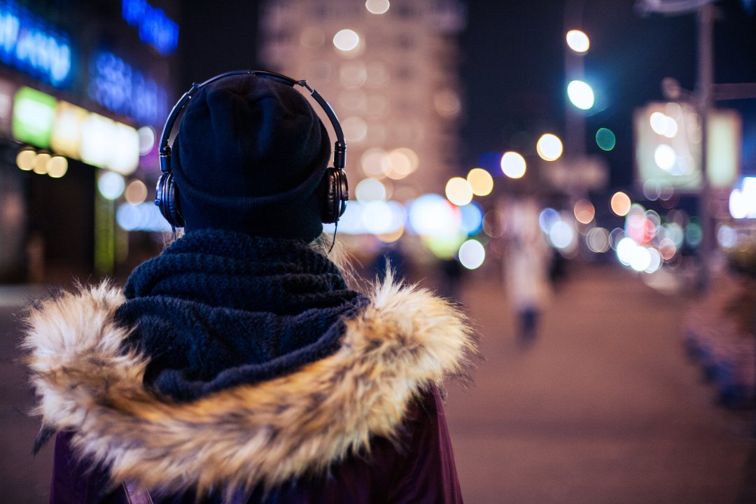 Person mit Kopfhörern spaziert durch nächtliche Strassen